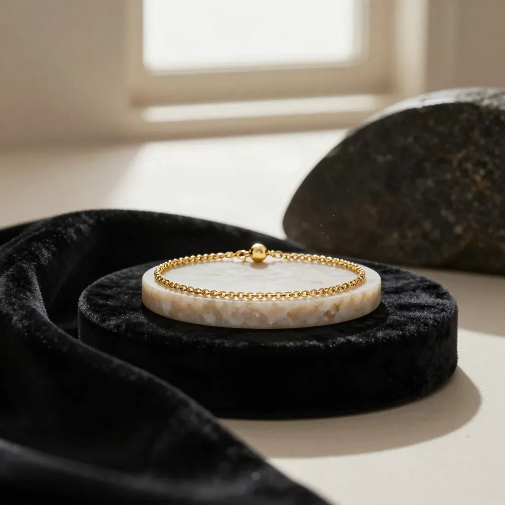 Gold chain bracelet suspended above black velvet and pale stone, studio-lit in luxury hero style.